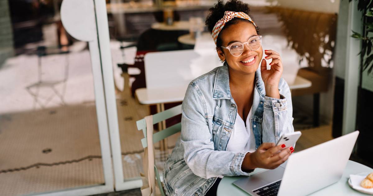 Zakenvrouw gebruikt laptop en smartphone in café