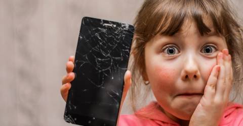 Meisje is geschrokken en heeft een mobiele telefoon in haar hand waarvan het glas gebroken is